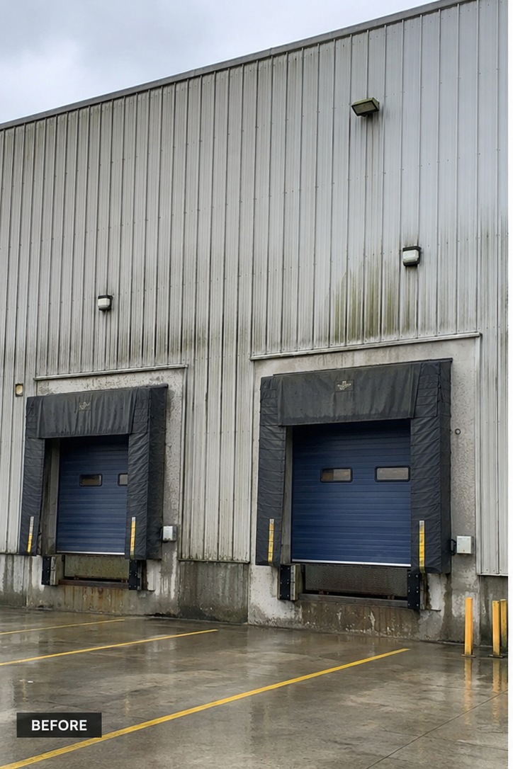 Industrial unit cladding streaked with algae and weathering above the loading bays before cleaning